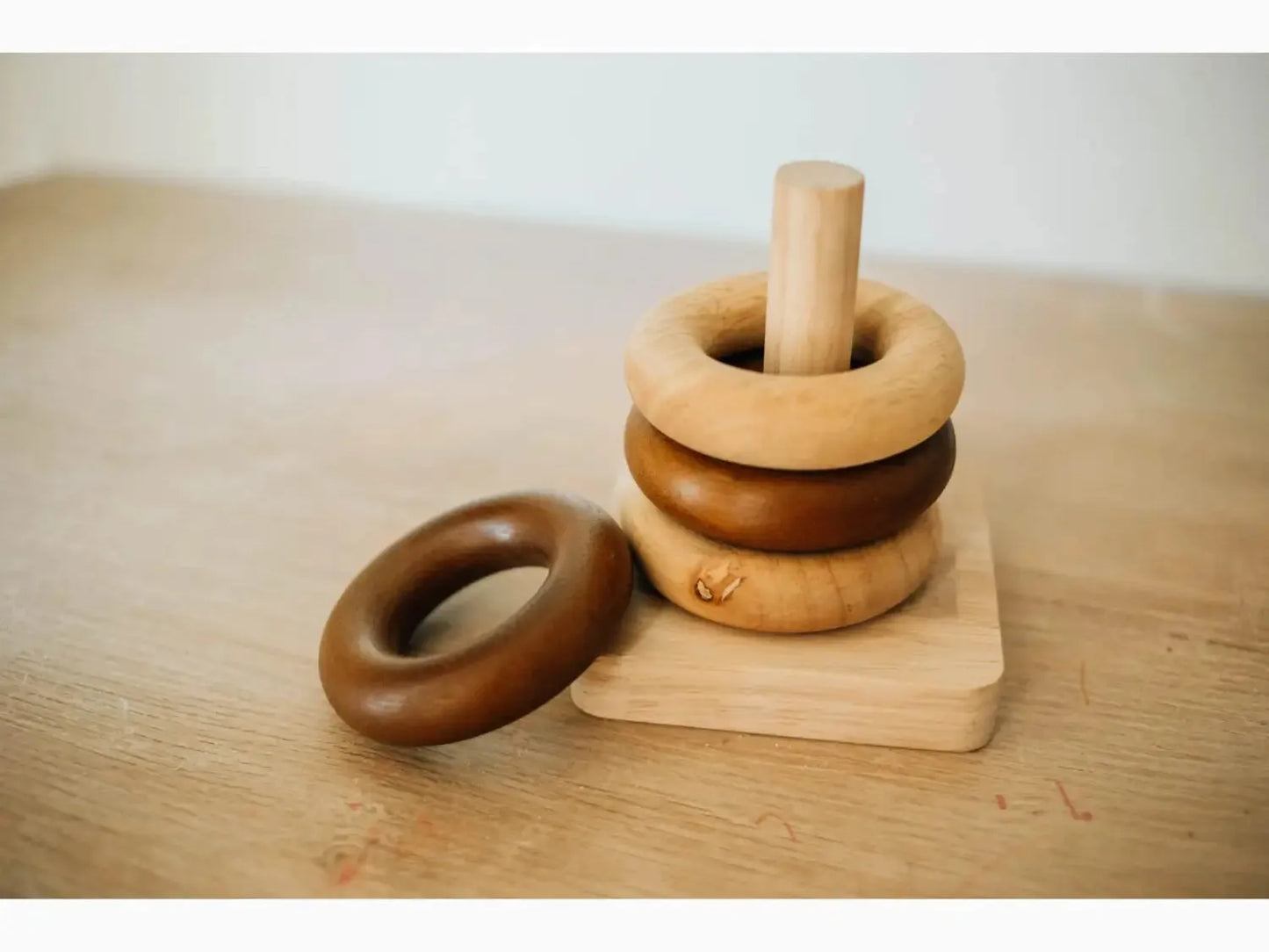 Wooden stacking toy with rings in earth-tone colors.