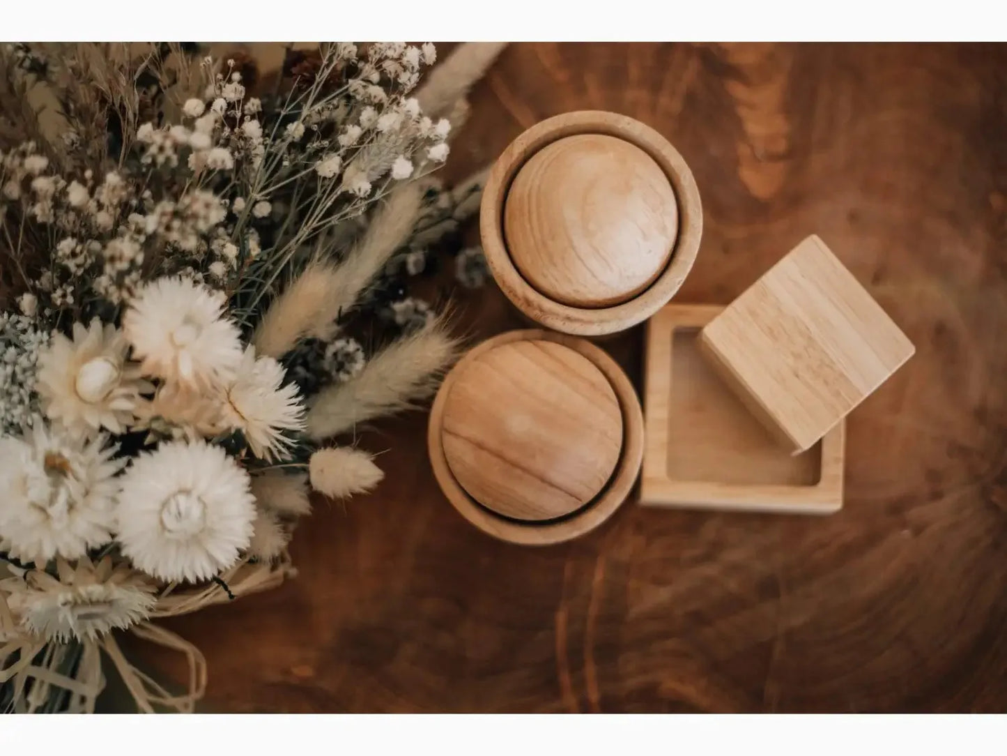 Bouquet of dried flowers alongside wooden boxes or containers.