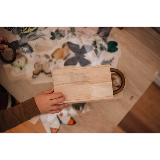 Wooden cutting board or serving plank held by a hand.