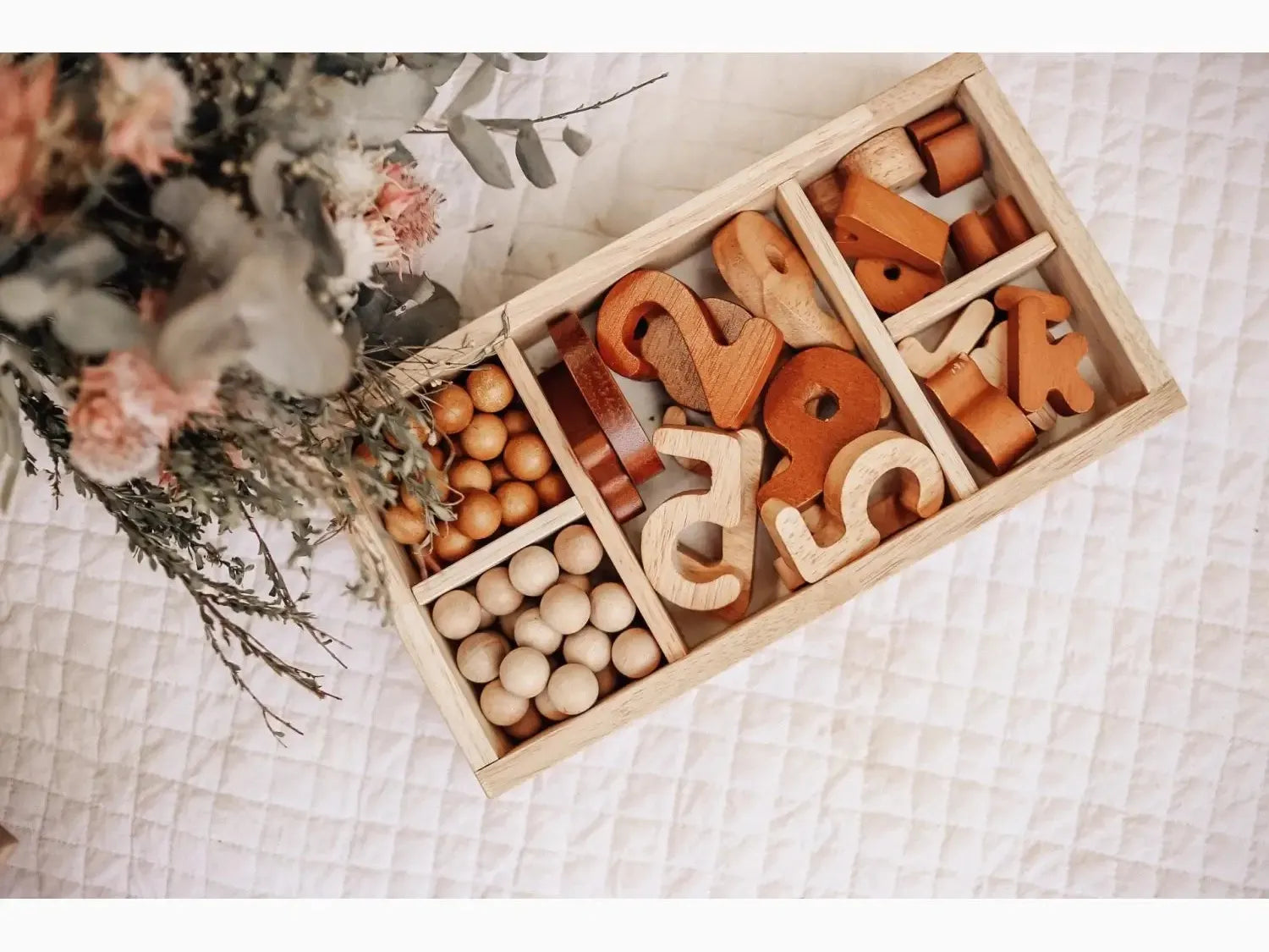 Wooden compartmentalized tray containing various wooden toys and beads.