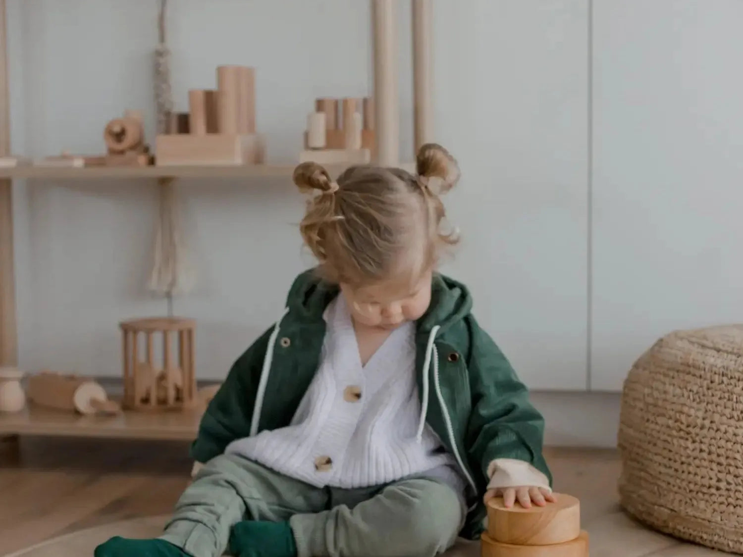 Young child sitting on the floor playing with wooden toys.