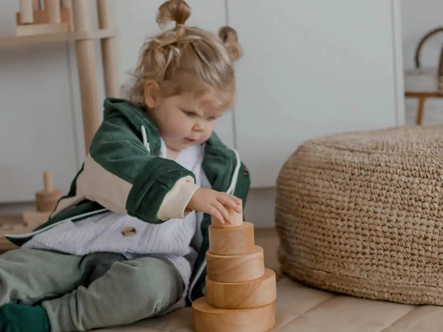 Child playing with a wooden stacking toy on the floor.