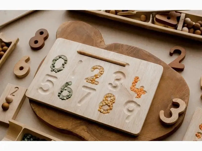 Wooden board with number-shaped indentations filled with various materials.