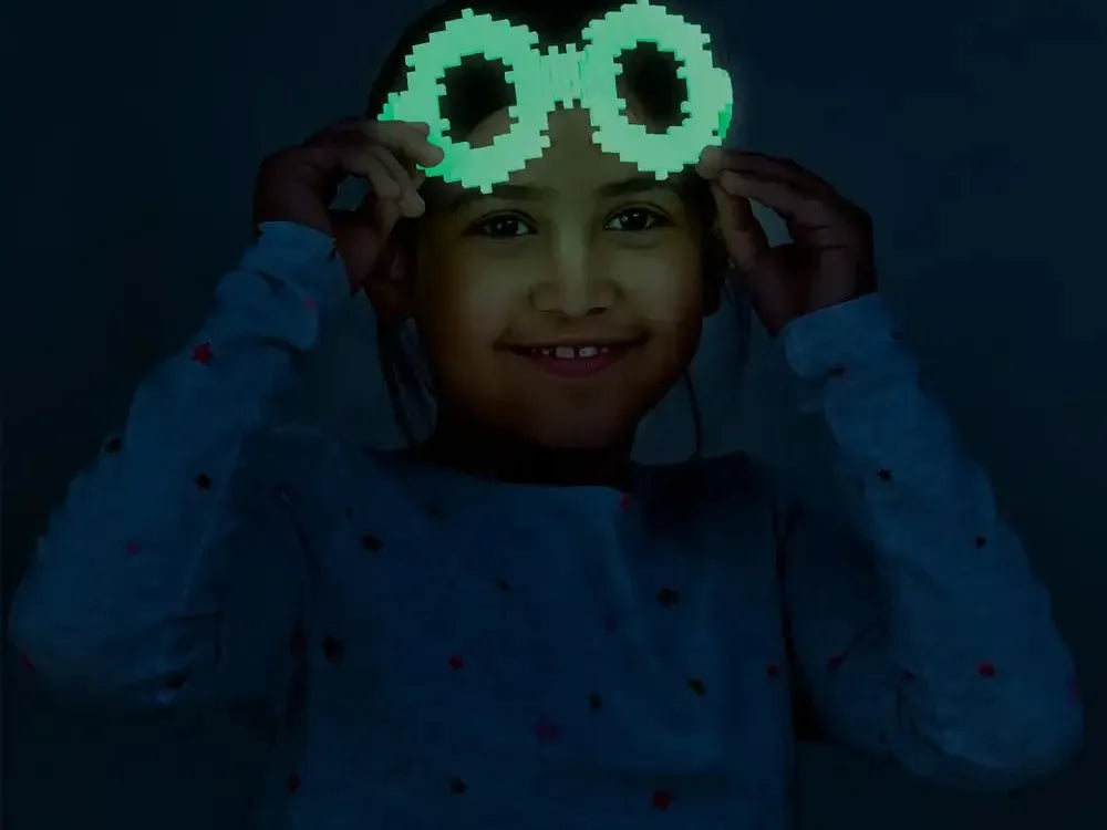 Glowing green pixelated glasses or goggles being held up to someone’s face.