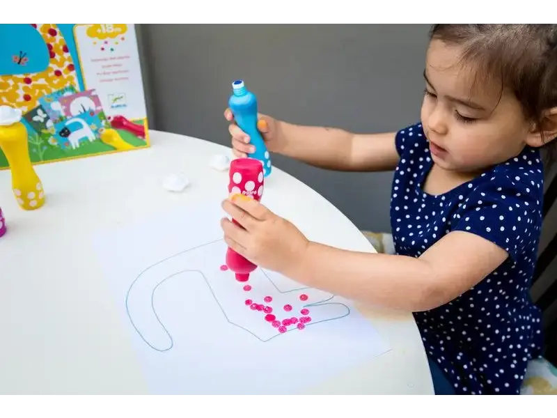 Child playing with a colorful drawing toy on a white table.