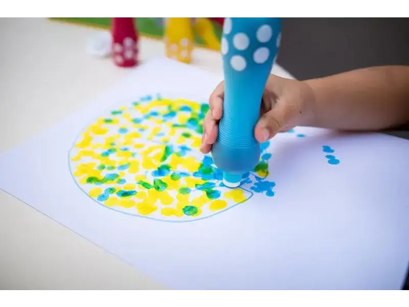 Dot marker being used to create a colorful circular pattern on paper.