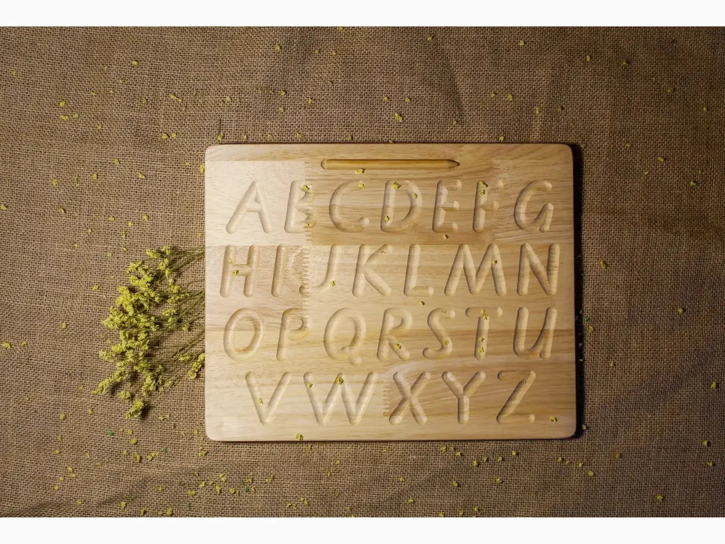 Wooden alphabet tracing board with uppercase letters engraved.