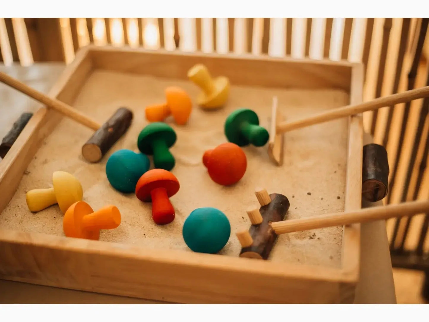 Wooden tray containing colorful wooden mushroom-shaped toys and mallets.
