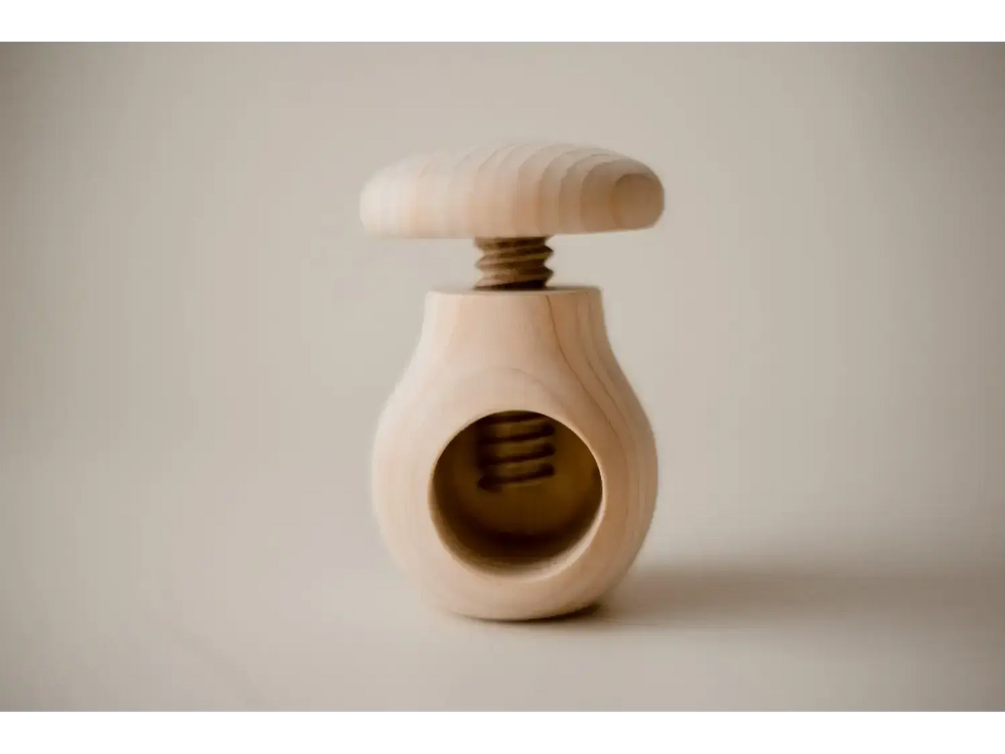 Wooden nutcracker with a round body and screw-top mechanism.