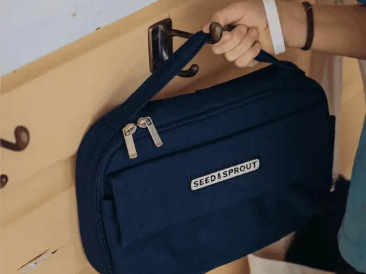 Navy blue ’Feed Leproud’ branded fanny pack or waist bag being hung on a hook.
