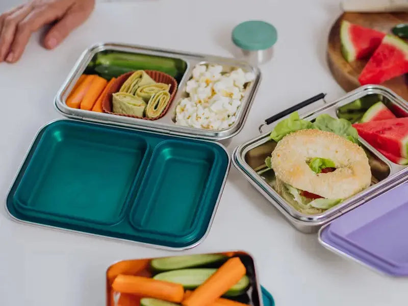 Bento-style lunch boxes filled with various healthy foods and snacks.