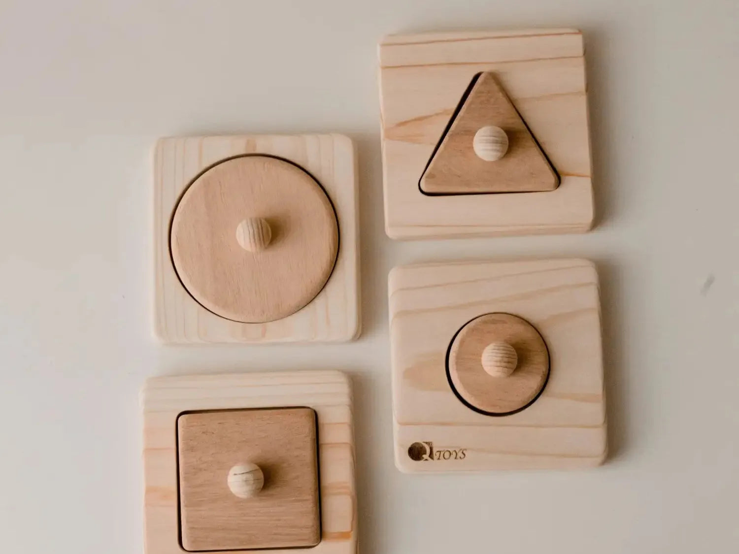 Set of wooden shape puzzles for children featuring circle, triangle, and square pieces with knobs.