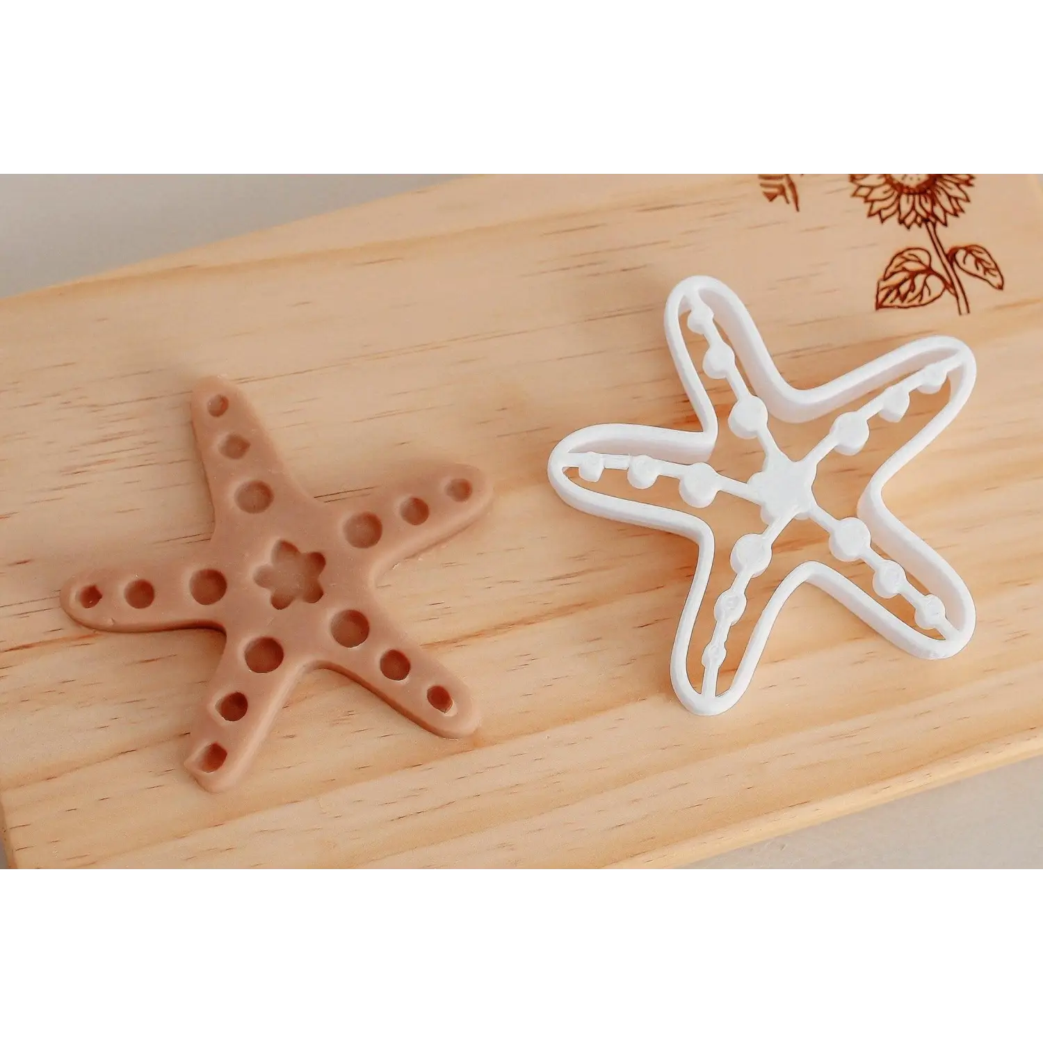 Two starfish-shaped cookie cutters, one brown and one white, on a wooden surface.