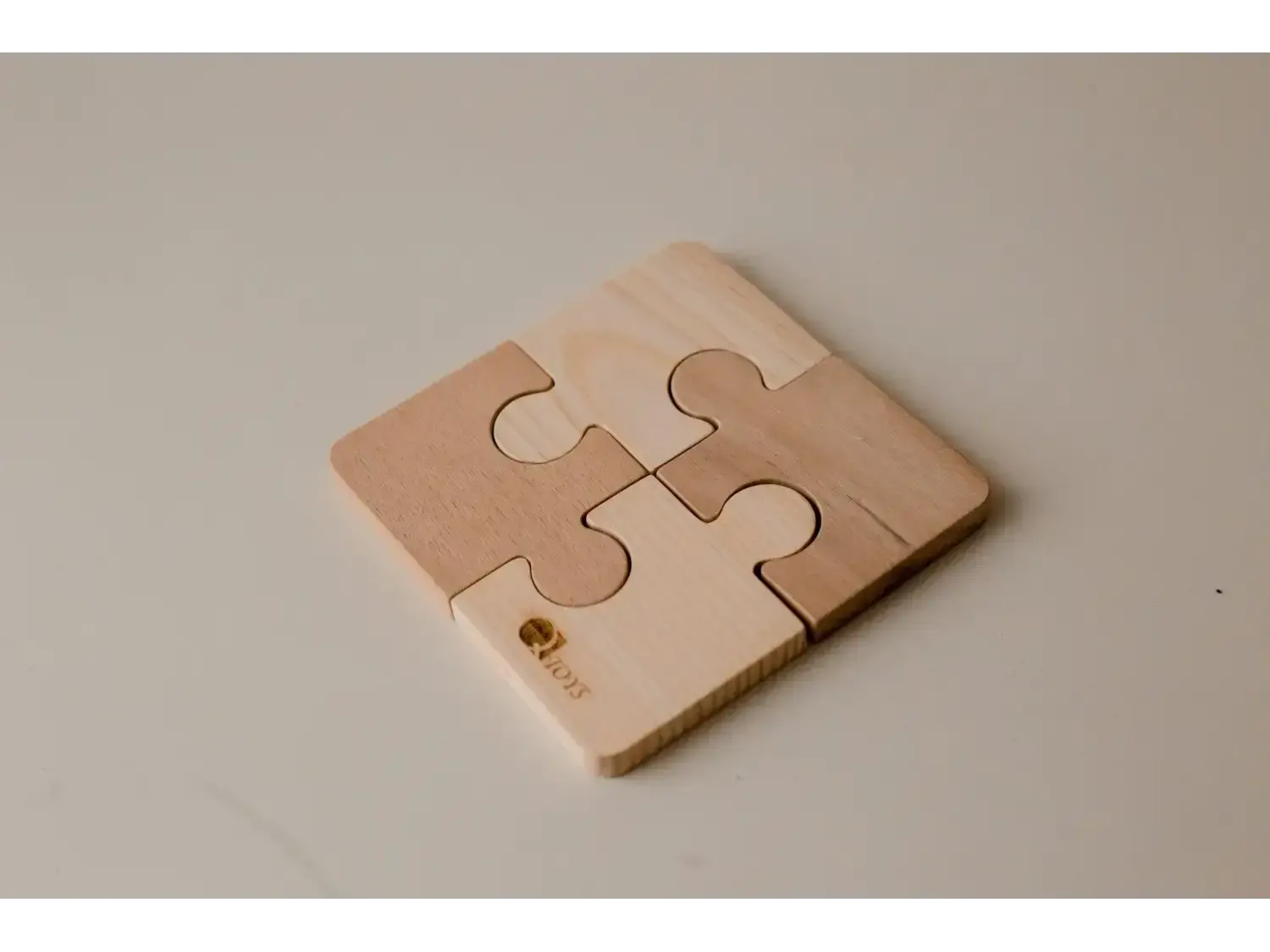 Four-piece wooden puzzle coaster with interlocking jigsaw shapes.