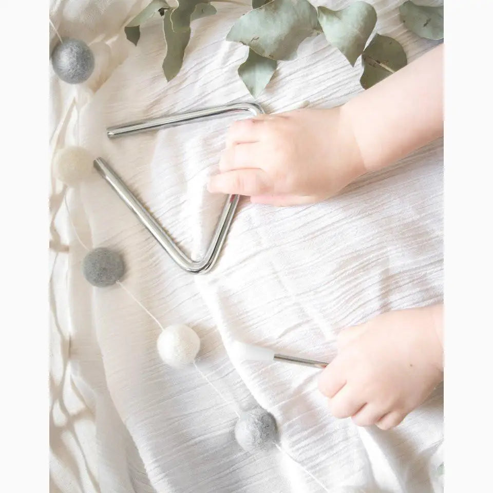 Triangle-shaped musical instrument, likely a triangle percussion instrument, with small hands nearby.