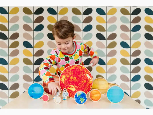 Child playing with a colorful model of the solar system.