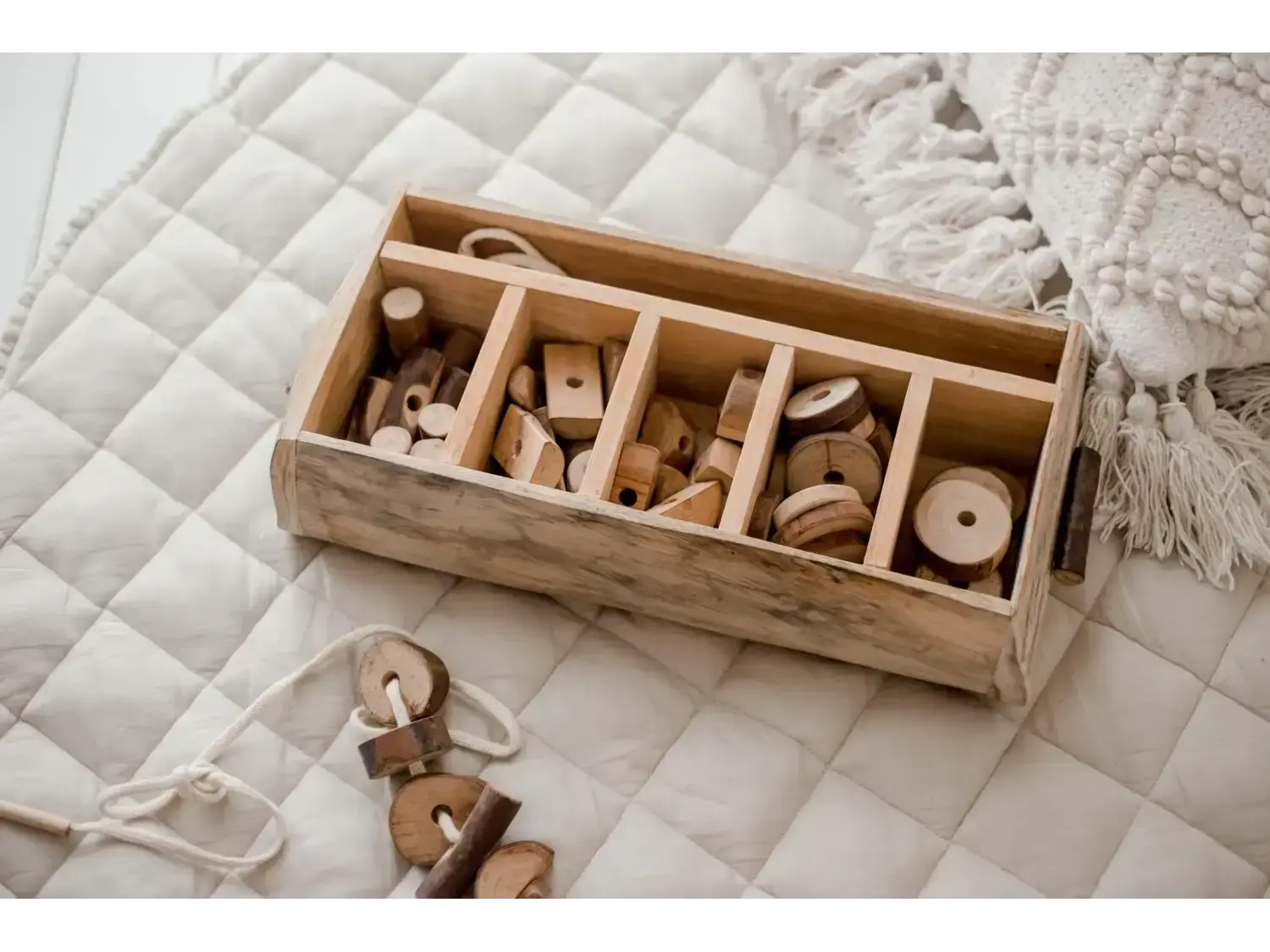 Wooden box with compartments containing various wooden toys and shapes.