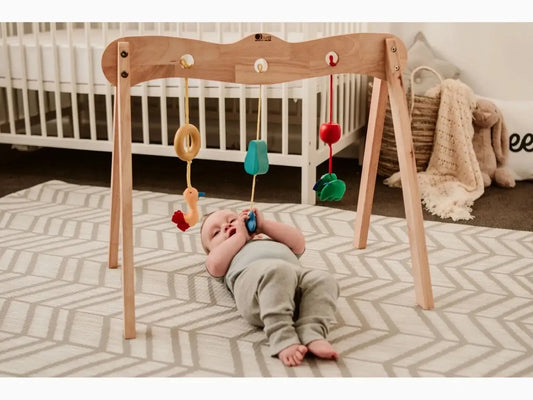 Wooden baby play gym with hanging toys.