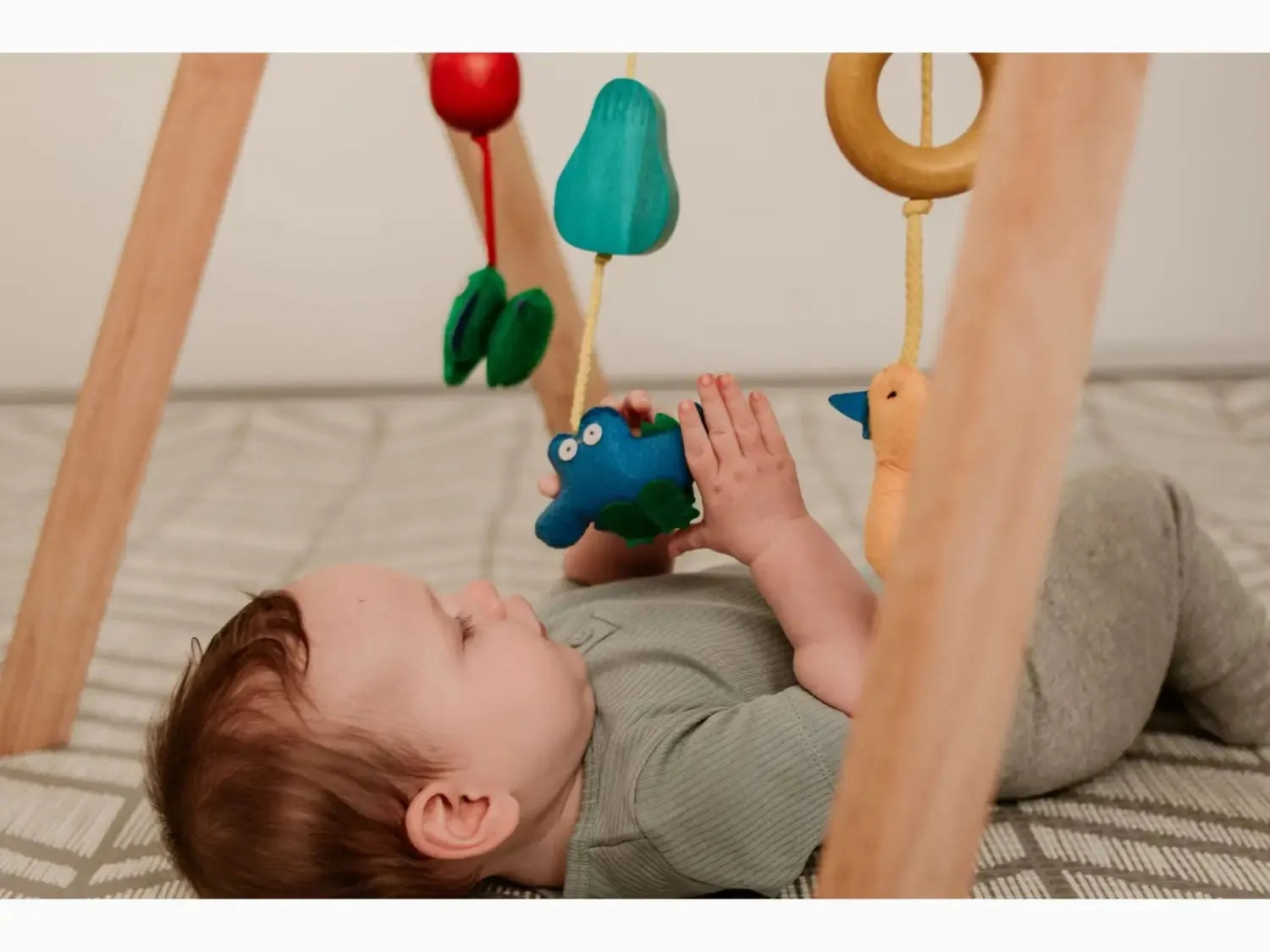 Baby playing with colorful hanging toys.