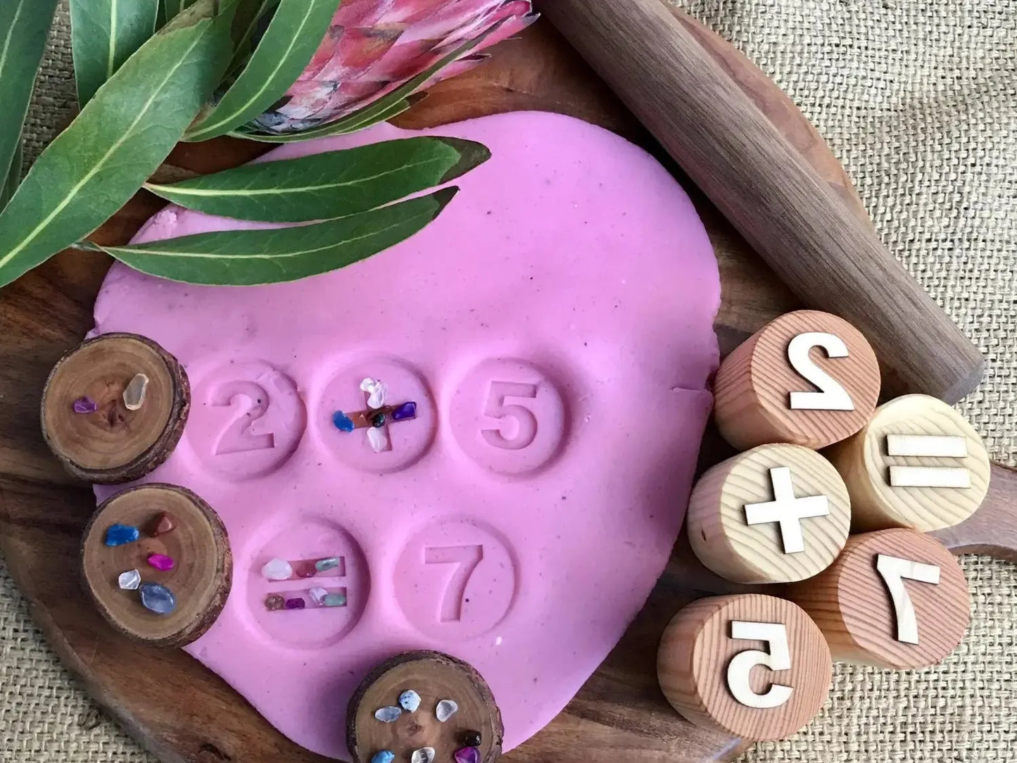 Pink heart-shaped playdough or clay with numbers and wooden discs imprinted on its surface.