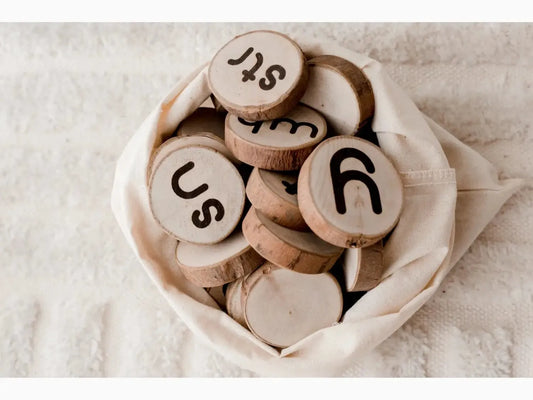 Wooden discs with letters and symbols carved on them, gathered in a fabric pouch.