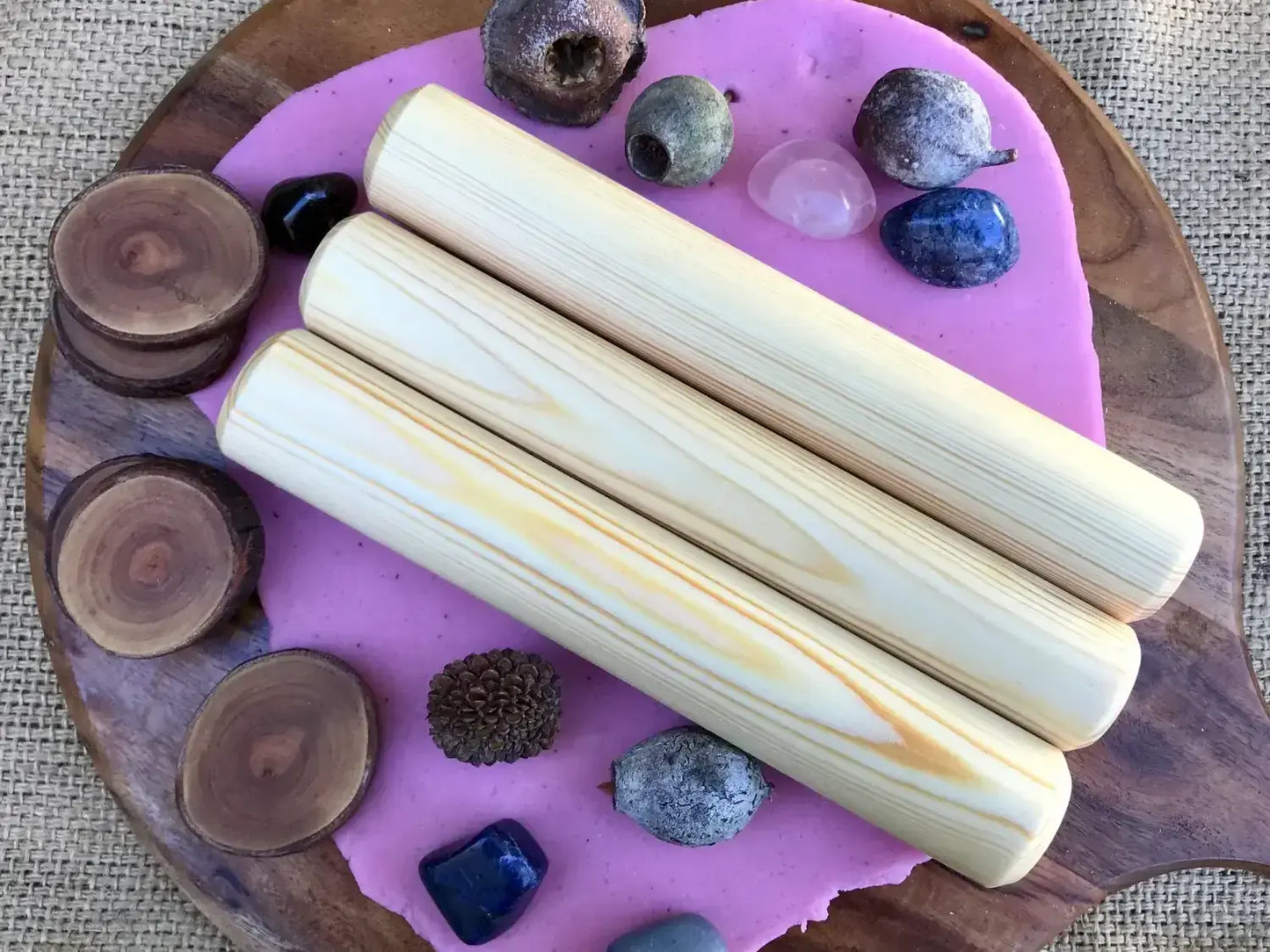 Wooden board with purple resin inlay holding crystals, stones, and palo santo sticks.