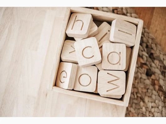 Wooden blocks with engraved letters in a box.
