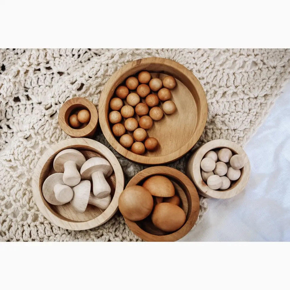 Wooden bowls containing various natural objects like eggs, mushrooms, and round items.