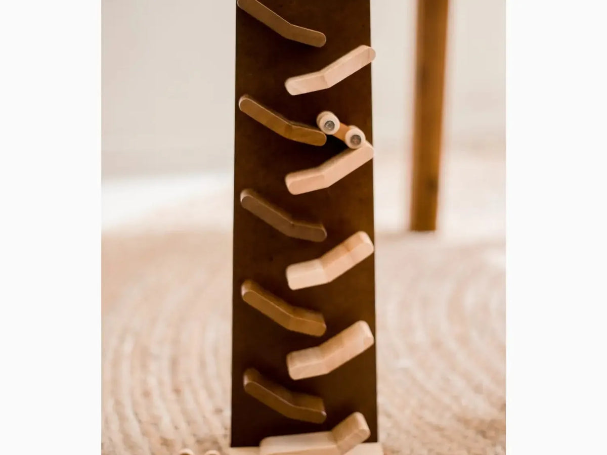Wooden zigzag track with alternating light and dark ramps for rolling balls.