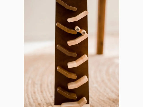 Wooden zigzag track with alternating light and dark ramps for rolling balls.