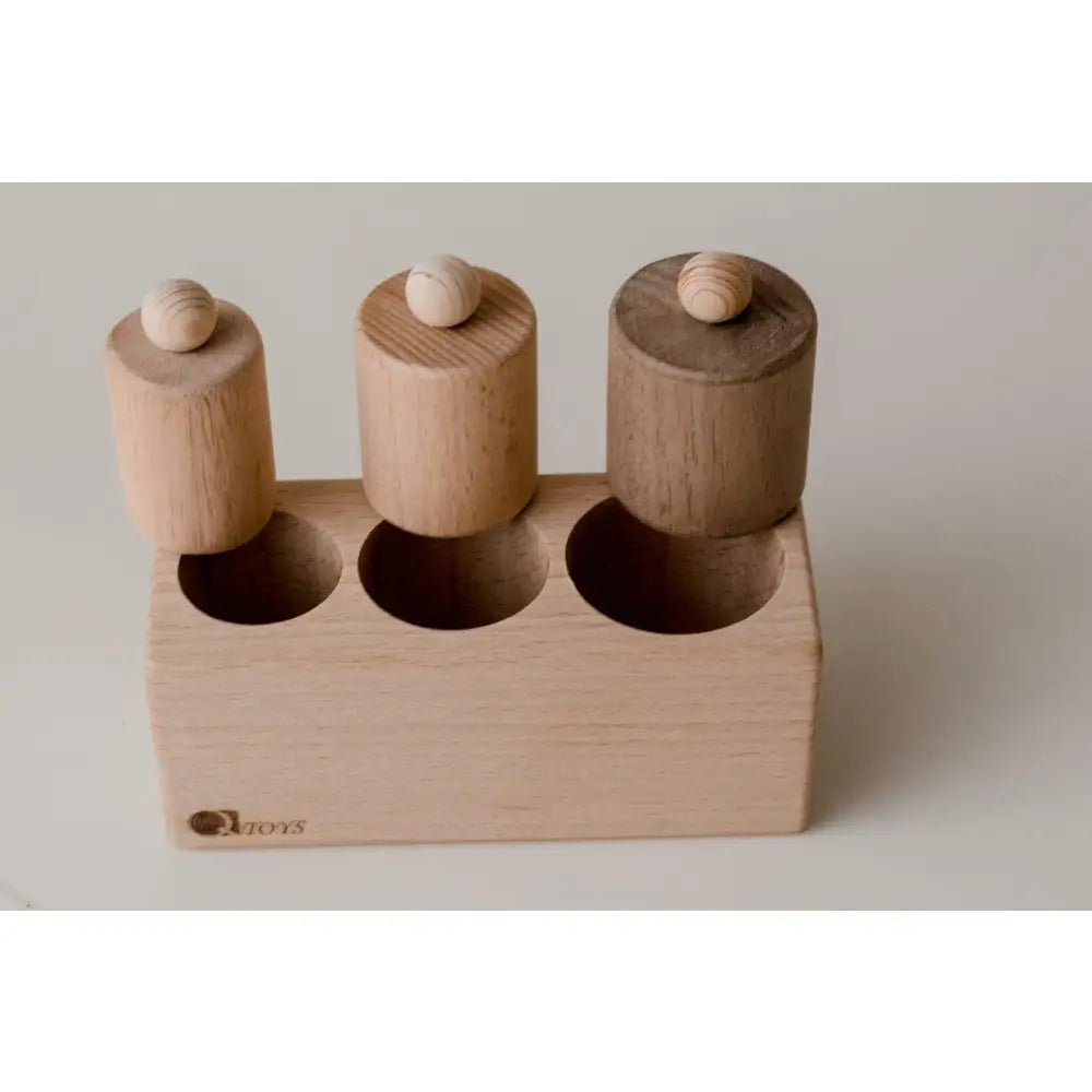 Wooden toy with three cylindrical pegs in a rectangular base.