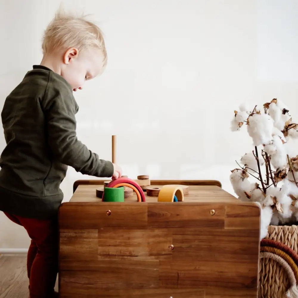 Wooden toy box or activity table with colorful shapes and objects on top.