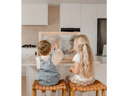 Two children sitting on wooden stools at a kitchen counter.