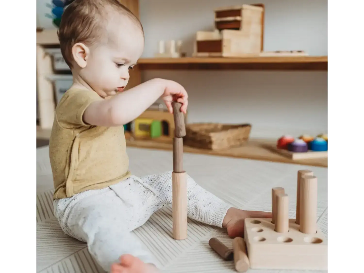 Young child playing with wooden building blocks on the floor.