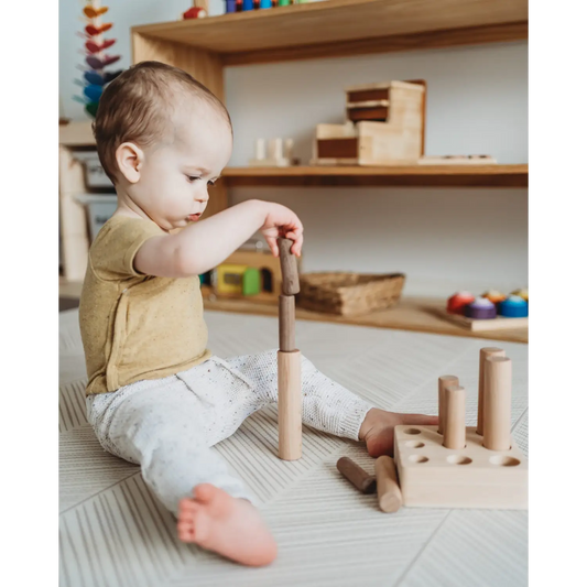 Young child playing with wooden building blocks on the floor.