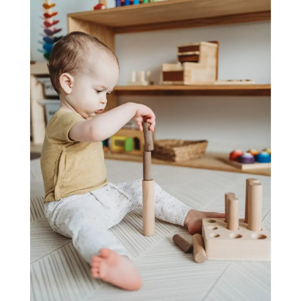 Young child playing with wooden building blocks on the floor.