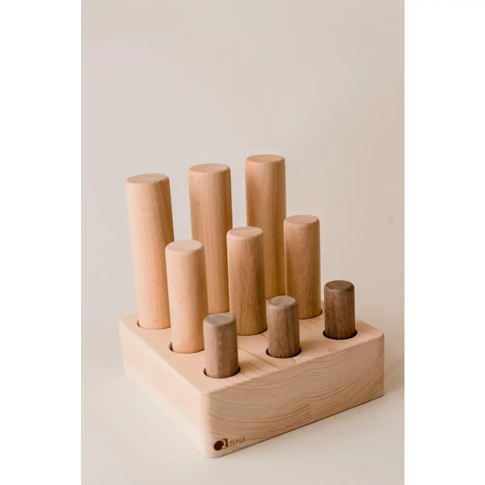 Wooden toy with cylindrical pegs of varying heights inserted into a base.