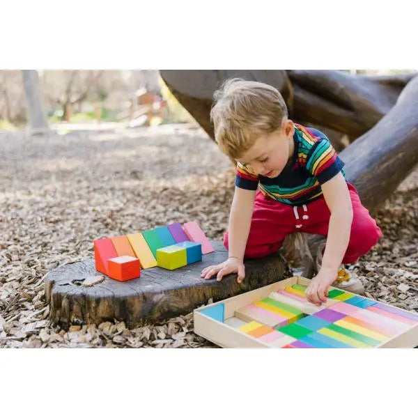 Child playing with colorful wooden blocks on a tree stump.