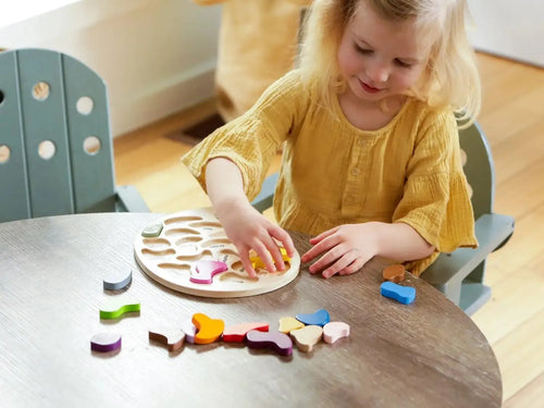 Young child playing with a wooden shape-sorting puzzle toy.