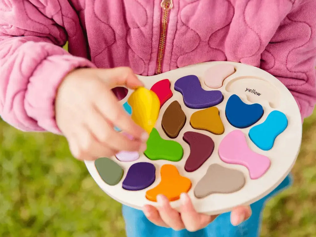 Colorful wooden shape-sorting puzzle toy held by small hands.