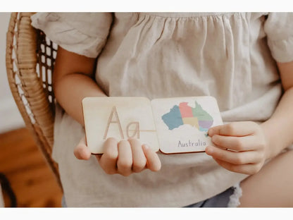 Wooden educational card or block with the letter ’A’ and colorful cloud shapes held by small hands.