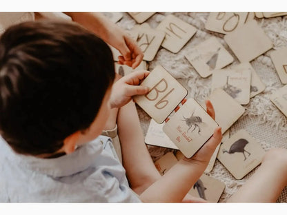 Child playing with alphabet flashcards on the floor.