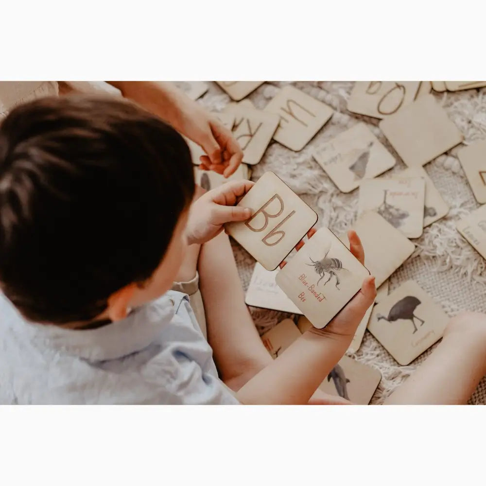 Child playing with alphabet flashcards on the floor.