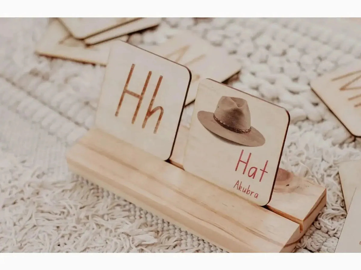 Wooden blocks with letters and a miniature hat on a stand.