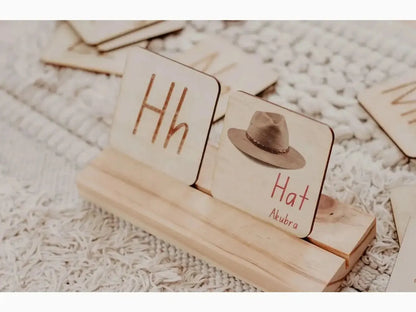 Wooden blocks with letters and a miniature hat on a stand.
