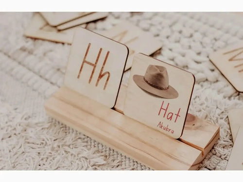 Wooden blocks with letters and a miniature hat on a stand.