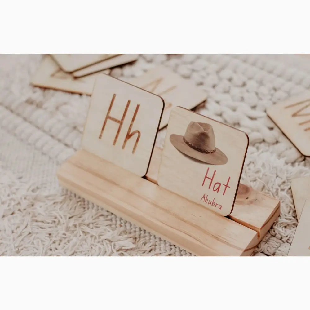 Wooden blocks with letters and a miniature hat on a stand.