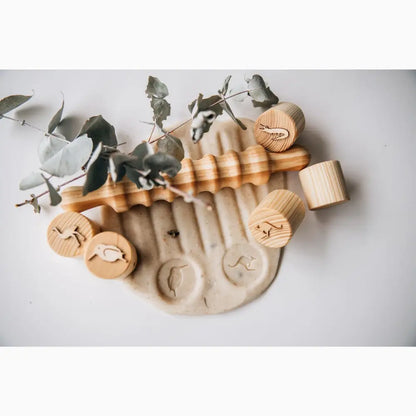 Clay or ceramic hand-shaped dish with wooden stamps and eucalyptus leaves.