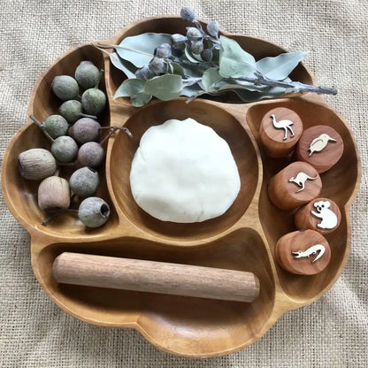 Wooden tray with compartments containing various natural objects and play materials.