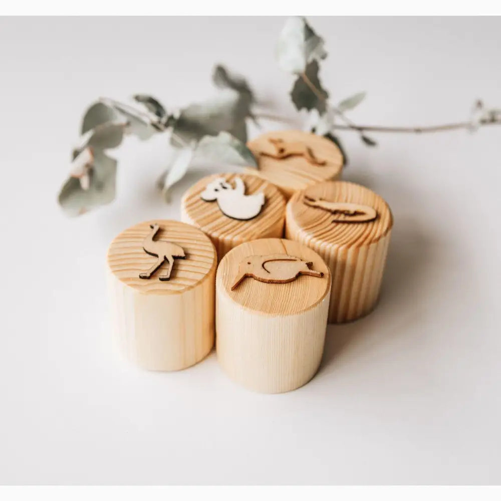 Wooden cylindrical stamps with animal shapes carved on top.